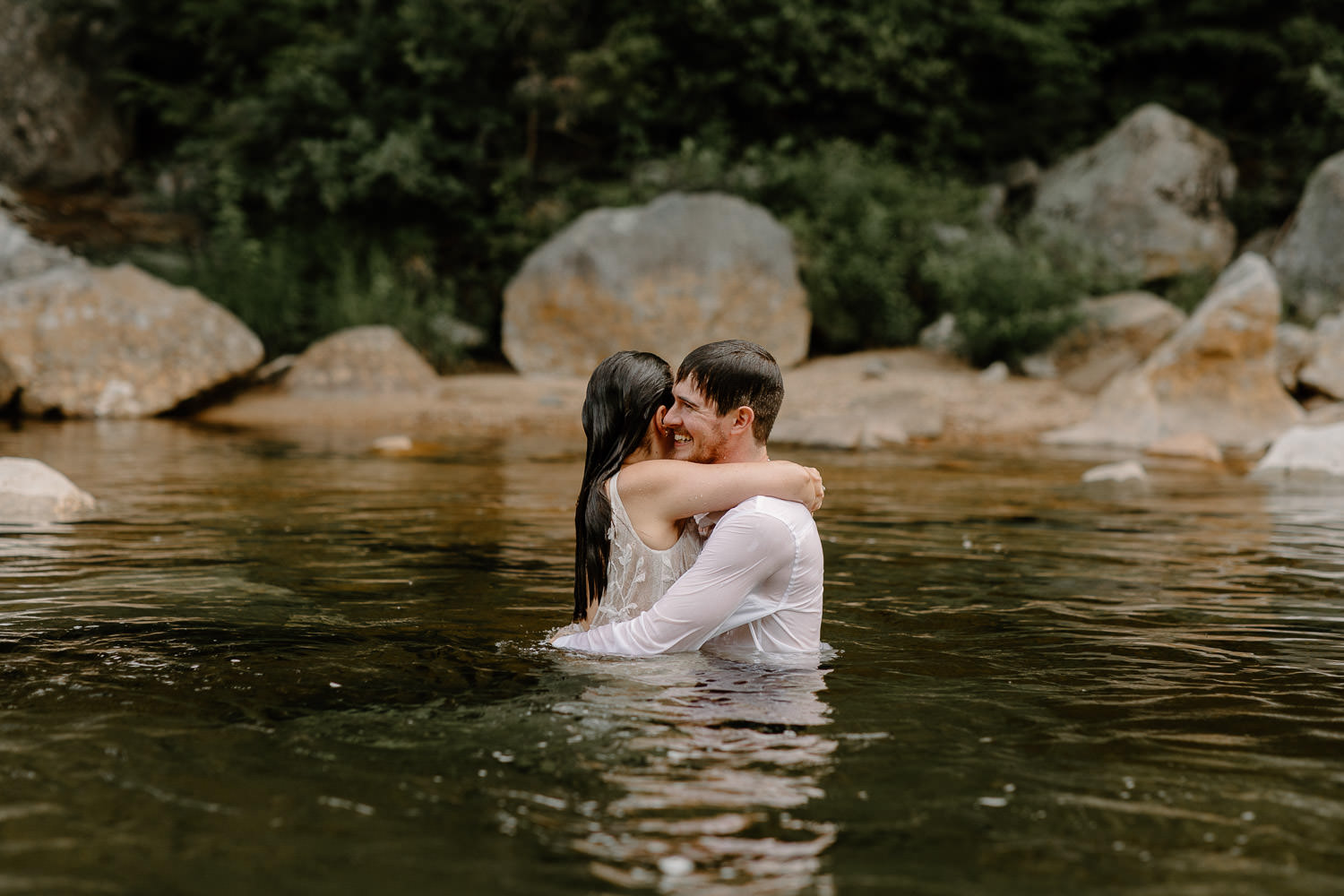 Bride and groom swimming in the river at elopement.