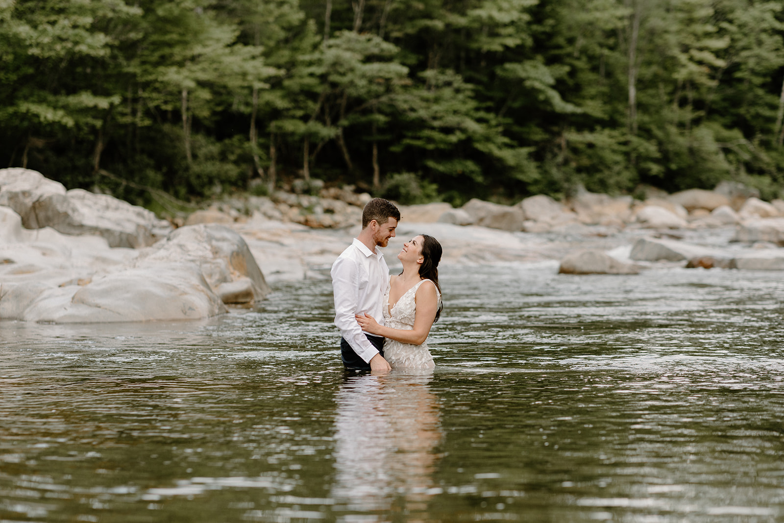 Bride and groom in river taking wedding photos
