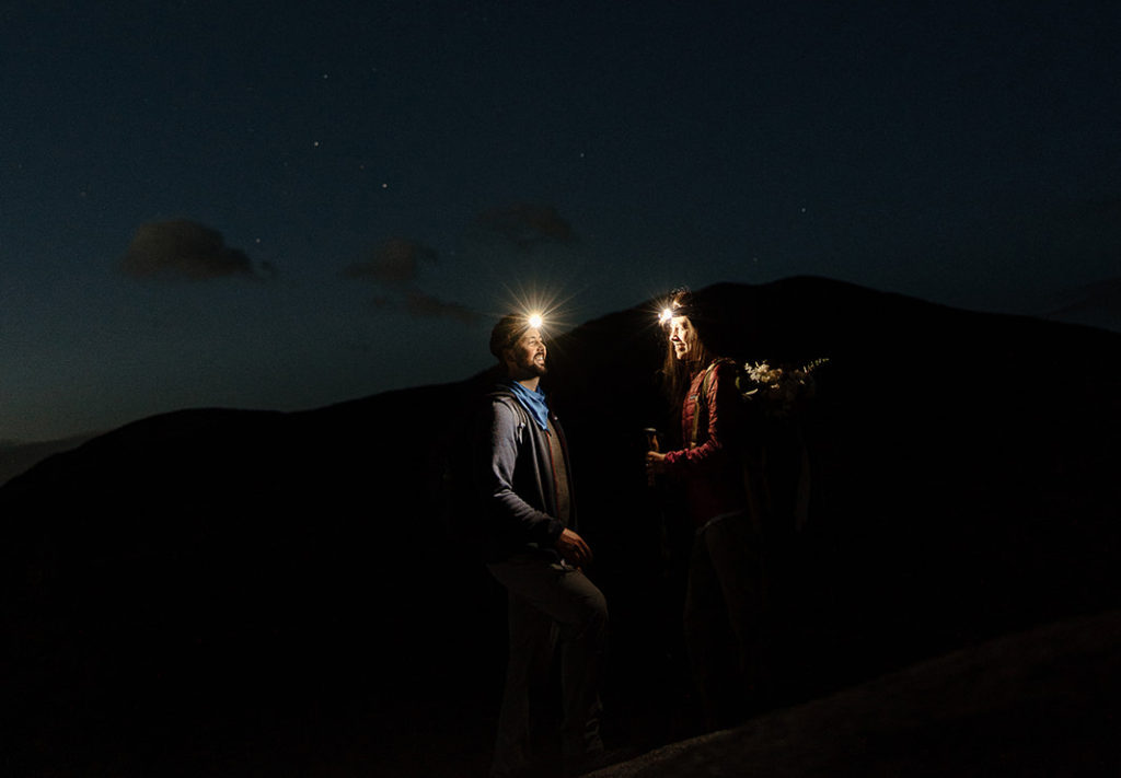 bride and groom hiking in the dark under stars at New Hampshire elopement
