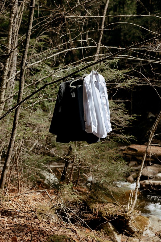 Grooms clothes hanging on tree at elopement